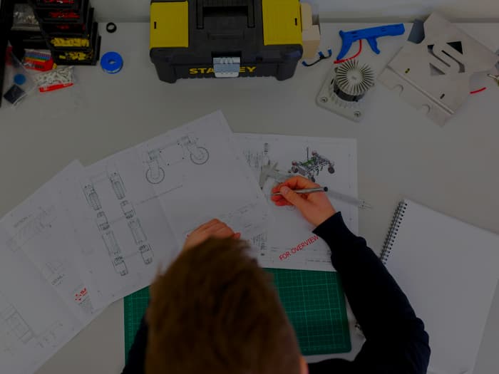 Technical drawings being marked up by hand at a workbench