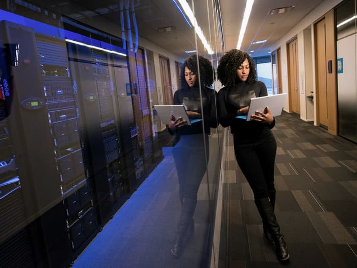 Engineers checking racked equipment in a data centre aisle