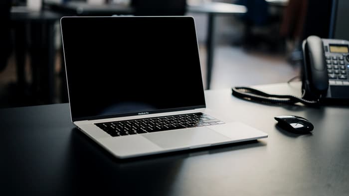 A laptop and desk telephone on an unattended office desk at night